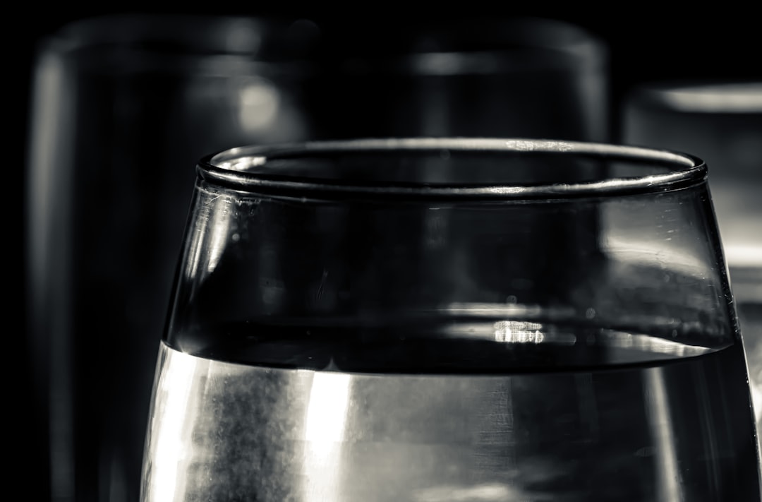 Glass of water on a dark surface, illustrating the role of saliva and hydration in chronic halitosis