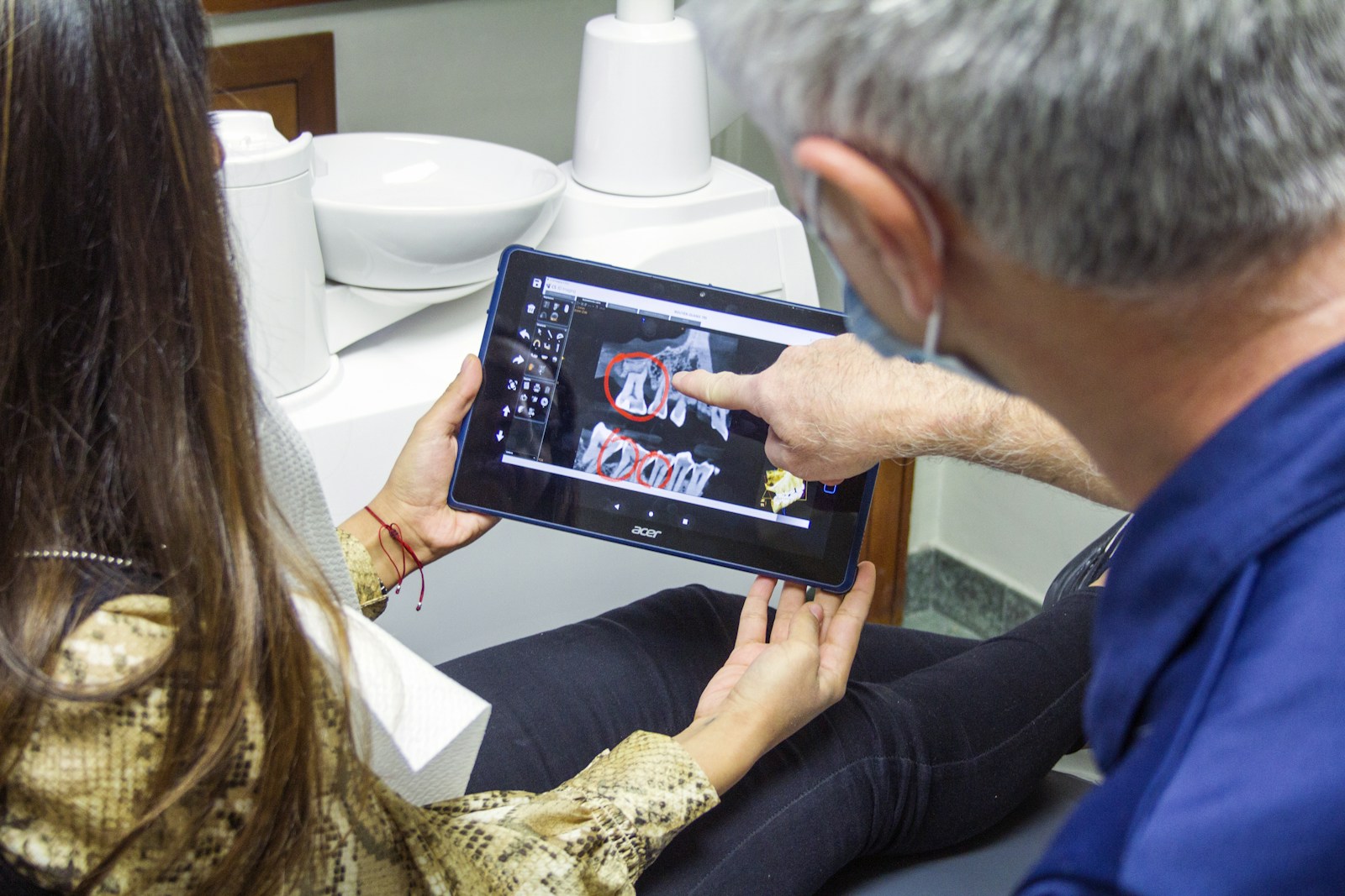 Patient reviewing a dental treatment plan and X-ray on a tablet during an implant consultation